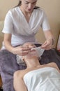 Beautician apply collagen mask to woman face. Cosmetologist works with a woman in a spa salon