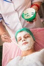 Beautician apply the cream-mask on the patient's face