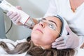 Beautician applying radio frequency microneedling handpiece to a woman`s face for skin tightening treatments at a beauty clinic