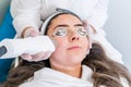 Beautician applying radio frequency microneedling handpiece to a woman`s face for skin tightening treatments at a beauty clinic Royalty Free Stock Photo