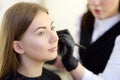 Beautician applying the tone of the foundation using special brush on face young beautiful model. Facial care and make up Royalty Free Stock Photo