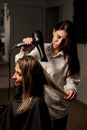 Beautician blow drying hair of woman client after giving new haircut at parlor