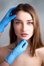 Beautician doctor`s hands in gloves touching face of attractive woman. Fashion blonde model after cosmetic treatment Royalty Free Stock Photo