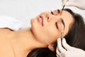 Beautician doing permanent eyebrows makeup. Closeup composition of beautiful woman face with thick brows In beauty salon