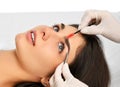 Beautician doing permanent eyebrows makeup. Closeup composition of beautiful woman face with thick brows In beauty salon Royalty Free Stock Photo