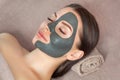 Beautician makes a black clay mask to rejuvenate the skin to beautiful woman.Cosmetology concept and treatment of problem skin