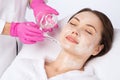 Beautician makes a face mask of a woman to rejuvenate the skin. Cosmetology treatment of problem skin on the face and body