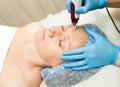 Beautician makes fractional mesotherapy to young woman. The cosmetic procedures for the face. Beauty treatments in the