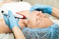 Beautician makes fractional mesotherapy to young woman. The cosmetic procedures for the face. Beauty treatments in the