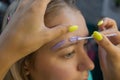 Beautician making depilation with wax strip young woman& x27;s eyebrows in spa center. Attractive woman getting facial care