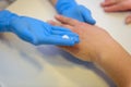 Beautician or manicurist in special medical gloves causes the cream on the woman`s hand at the table in the Spa, close-up Royalty Free Stock Photo