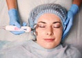 Beautician massaging woman face with facial roller. Royalty Free Stock Photo