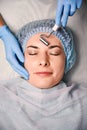 Beautician massaging woman forehead with facial massager. Royalty Free Stock Photo