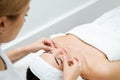 Beautician massaging woman`s cheeks. Attractive girl having facial treatment and massage. The young woman is lying and relaxingin Royalty Free Stock Photo