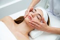 Beautician massaging woman`s face. Attractive girl having facial treatment and massage. The young woman is lying and relaxingin