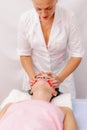 Beautician massaging woman`s face. Attractive girl having facial treatment and massage. The young woman is lying and relaxingin Royalty Free Stock Photo