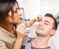 Beautician plucking a beautiful man eyebrows with tweezers in a beauty salon