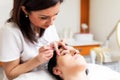 Beautician plucking eyebrows with tweezers to a girl lying in beauty salon Royalty Free Stock Photo