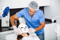 Beautician preparing female client for procedure of phototherapy Royalty Free Stock Photo