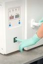 Beautician in protective gloves starts the machine for disinfection of tools before the depilation procedure. Royalty Free Stock Photo