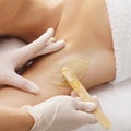 Beautician is removing hair from young female armpits with hot wax. Girl has a beauty treatment procedure. Depilation Royalty Free Stock Photo