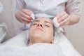 Beautician washes woman`s face using cotton pads. Preparing for a cleaning face