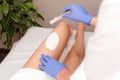 Beautician waxing female legs in spa center. Removing unnecessary hair on the legs. Procedure sugaring in a beauty salon