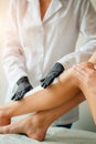 Beautician waxing a woman leg applying a strip of material over the hot wax Royalty Free Stock Photo