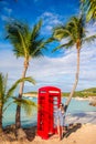 Beautiftul woman near red phone booth in Dickenson`s bay Antigua. Royalty Free Stock Photo