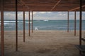 Beautiful abandoned beach resort with wooden canopy tent and sun bed near stormy sea shore in dead season Royalty Free Stock Photo