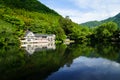 Beautiful abundant natural green mountain landscape symmetrical reflection on fresh lake Kinrin with buildings during springtime