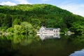 Beautiful abundant natural green mountain slope reflection on fresh lake Kinrinko with buildings during springtime