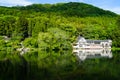 Beautiful abundant natural shades of green mountain background reflection on fresh lake Kinrinko with buildings in springtime