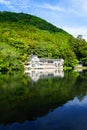 Beautiful abundant natural shades of spring green mountain background mirror reflection on fresh lake Kinrinko with buildings