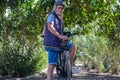 Beautiful active senior man with electro bikes standing outdoors in the park. Happy elderly grandfather running in nature with his Royalty Free Stock Photo