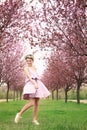 Beautiful active young woman in park with blossoming trees on spring day