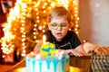 Beautiful adorable seven eight year old boy in grey shirt, celebrating his birthday, blowing candles on homemade baked cake, Royalty Free Stock Photo