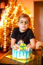 Beautiful adorable seven eight year old boy in grey shirt, celebrating his birthday, blowing candles on homemade baked cake, Royalty Free Stock Photo