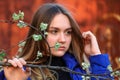 adorable teenage girl with long hair, out of focus, in front of a branch with young leaves