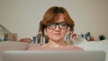 Beautiful Adult Lady with Laptop in a Cozy Room. Screen is Reflecting in Glasses