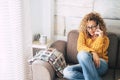 Beautiful adult people having phone call at home -curly caucasian blonde woman sitting on the sofa with cellular -  Middle age Royalty Free Stock Photo