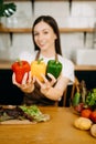 beautiful adult woman with bell peppers looking at camera while making salad at kitche. healthy food concept Royalty Free Stock Photo