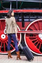 Beautiful adult woman traveler with a suitcase on the platform near the huge wheels