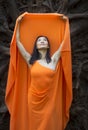Adult woman in orange dress, dancing under tree roots Royalty Free Stock Photo