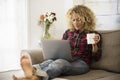 Beautiful adult young woman at home with laptop computer lay down on the couch - concept of alternative office and workstation - Royalty Free Stock Photo