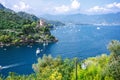 Beautiful aerial daylight view from top to boats on water, colorful houses and villas in Portofino town of Italy. Tourists walking