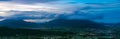 Beautiful aerial panoramic shot of green fields under a cloudy sky during the sunset Royalty Free Stock Photo