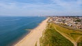 A beautiful aerial seaside view with sandy beach, crystal blue water, groynes breakwaters and green vegetation dunes along a