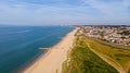 A beautiful aerial seaside view with sandy beach, crystal blue water, groynes breakwaters and green vegetation dunes along a