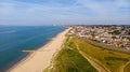 A beautiful aerial seaside view with sandy beach, crystal blue water, groynes breakwaters and green vegetation dunes along a